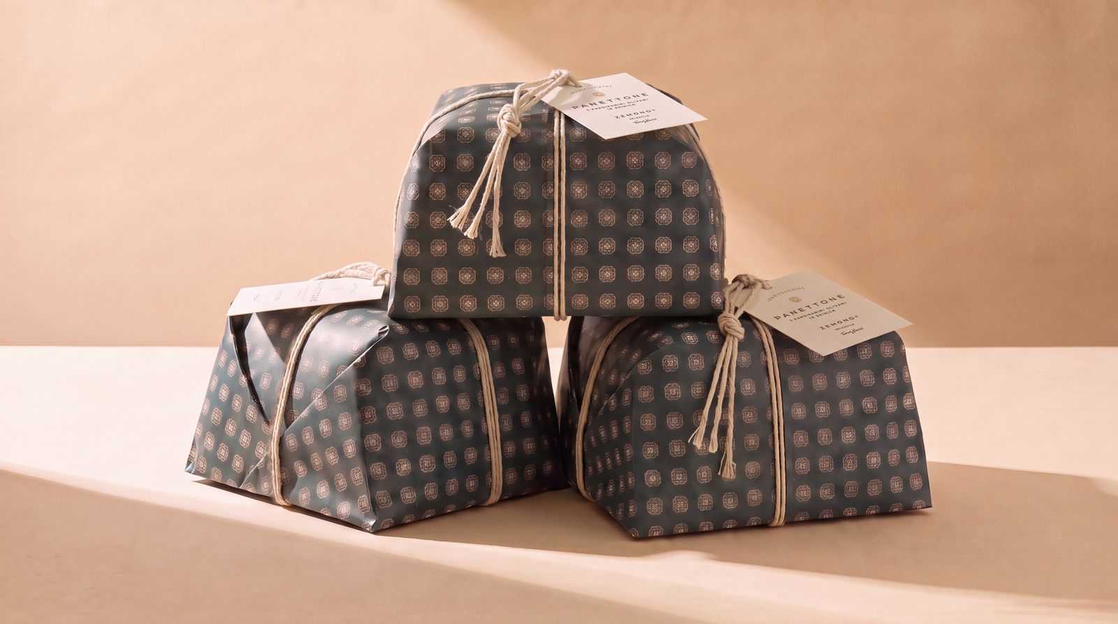 Three wrapped panettoni stacked on a warm beige ground