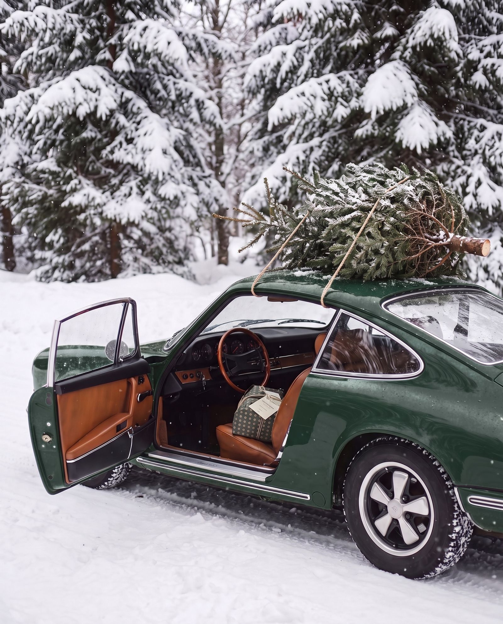 Green vintage car in the snow, a wrapped panettone on the seat