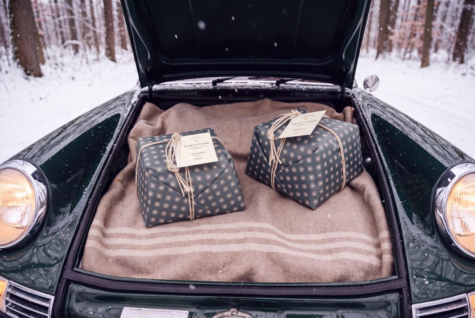 Two panettoni in the open front boot of a green vintage car
